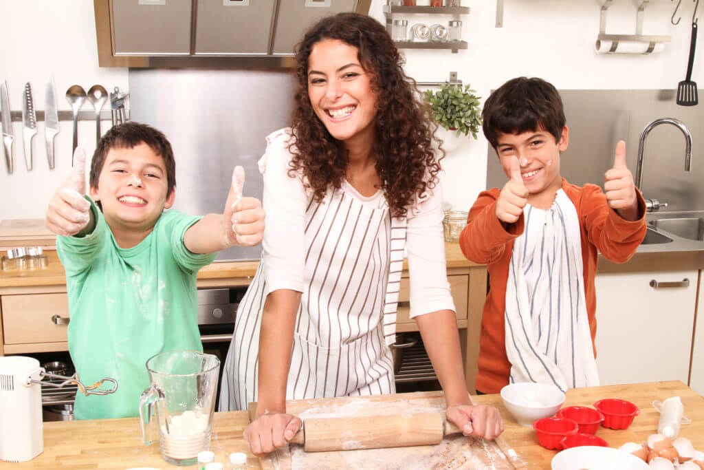 Smiling mom in kitchen and kids with thumbs up