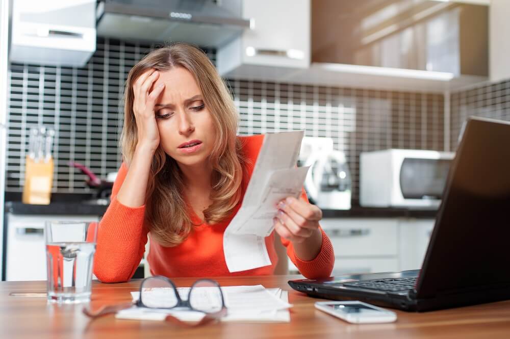 woman stressed over bills, with a hand on her head