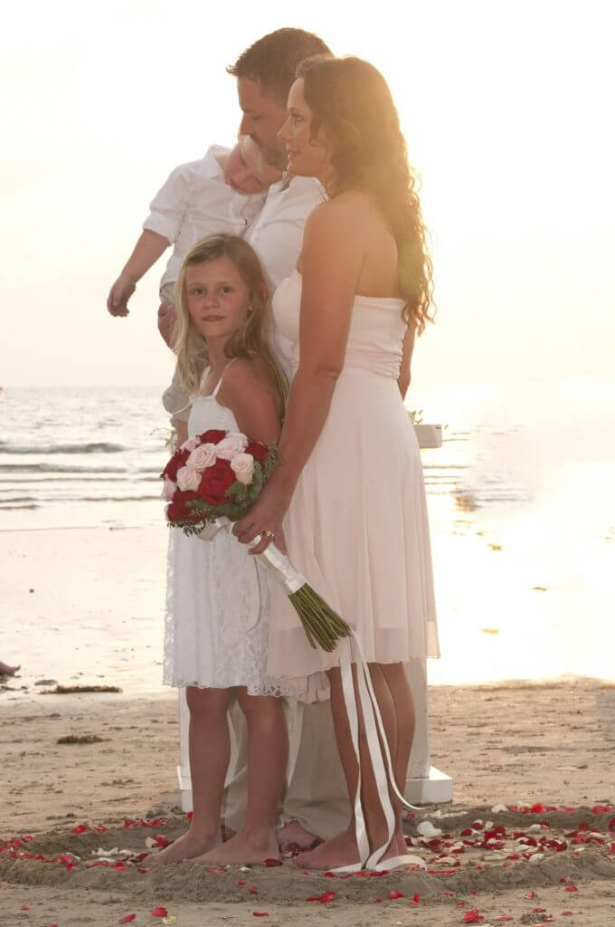 bride and groom and two children at their wedding on the beach