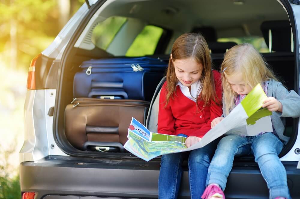 Kids looking at a map in a car's trunck