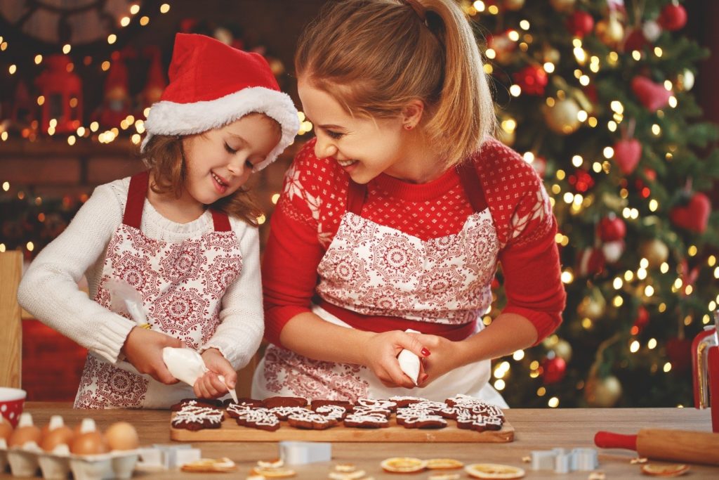woman and child wearing Christamas hats, making cookies