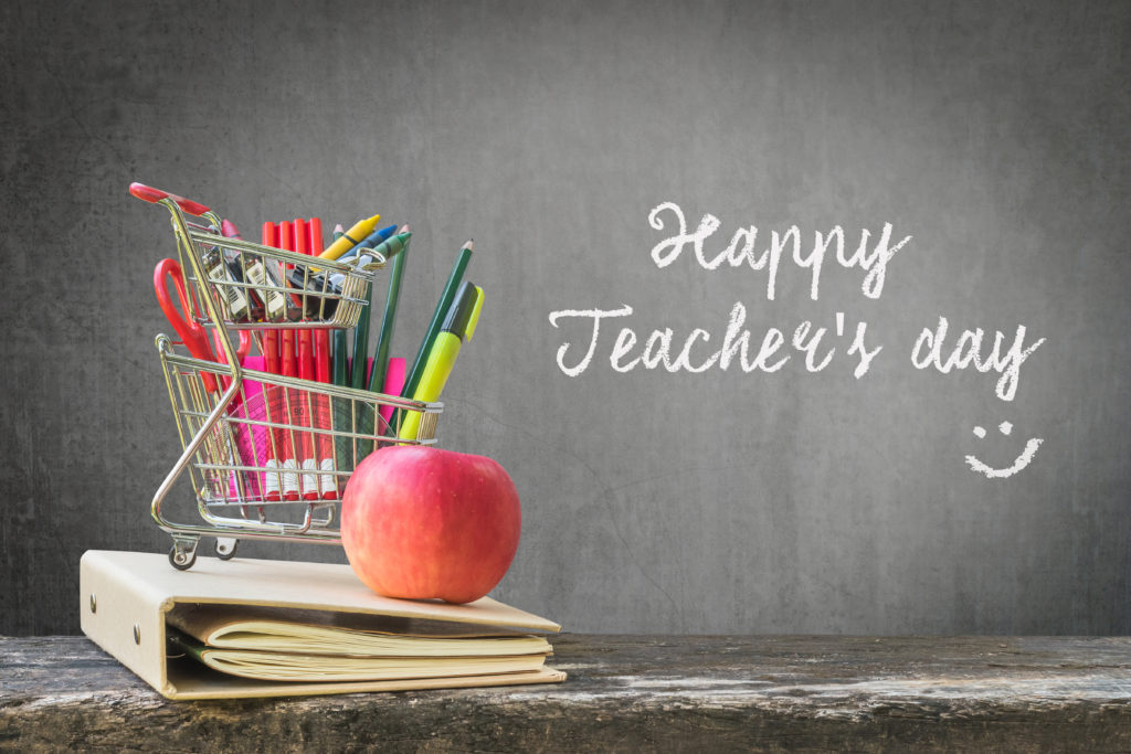 blackboard written with chalk that says "Happy teachers day", an apple and pencils