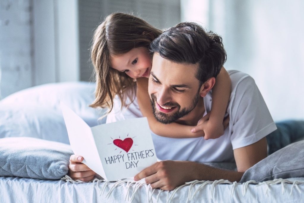dad reading a card with a heart, and his daughter hugging him