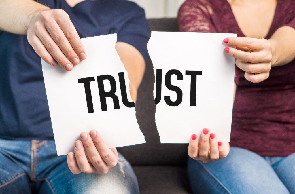 two people tearing up a trust poster