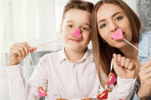 woman and child holding heart lollipops near their mouths
