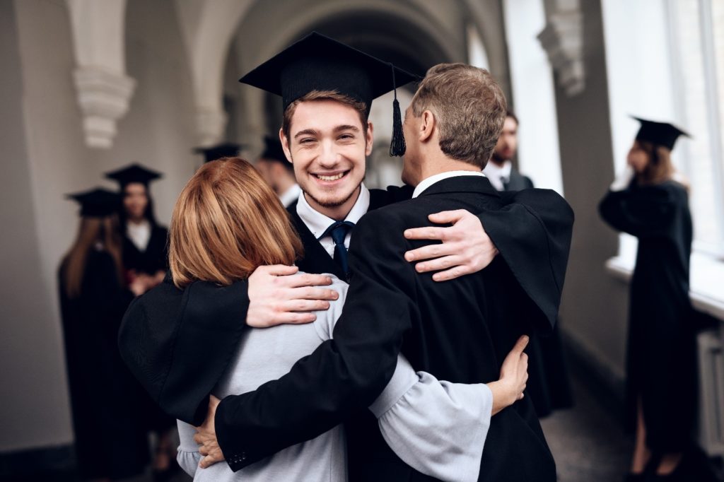 parents hugging their graduate son