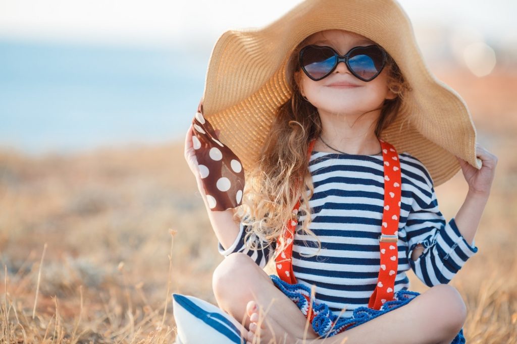 little girl on beach, wearing a big hat