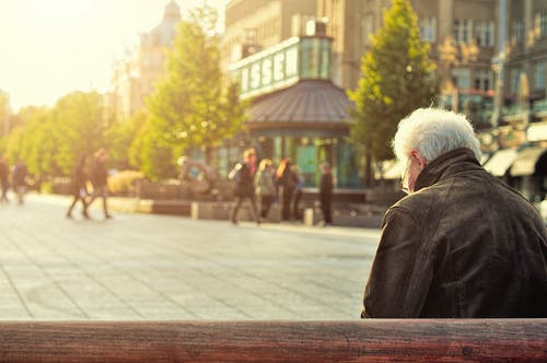 elderly man sitting at bench and looking down