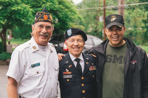three men of varying ages standing next to each other wearing military uniforms