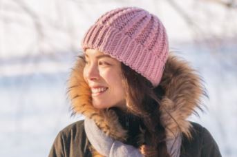 woman in winter coat and hat smiling and looking to her right
