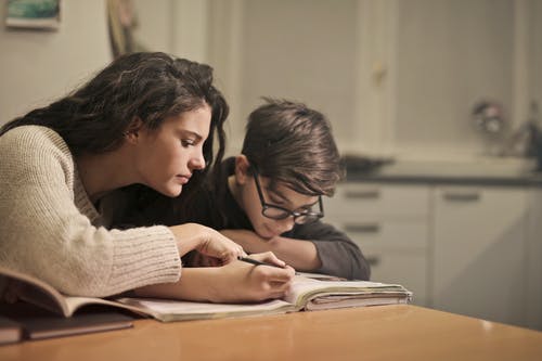woman helping child do homework at table