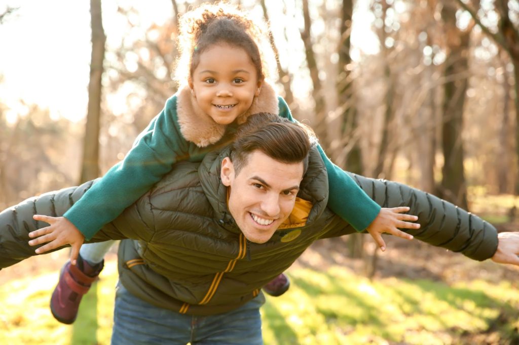 daughter balancing on dad's shoulders with arms stretched out to the sides