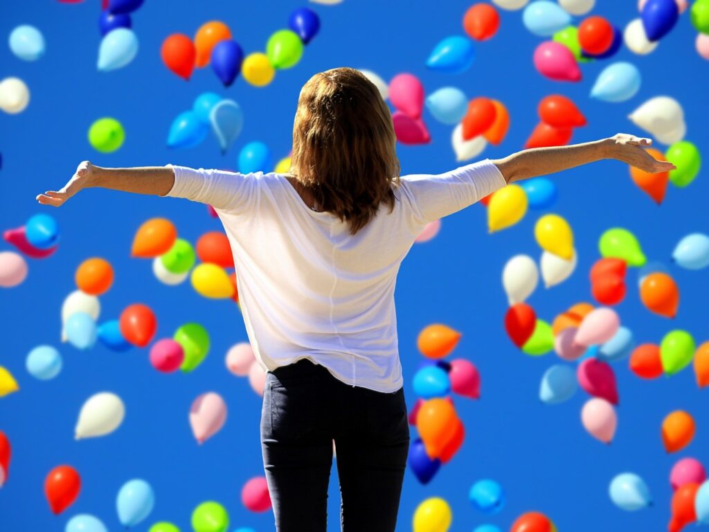A woman is celebrating her ability to reframe failure. She is surrounded by colorful balloons
